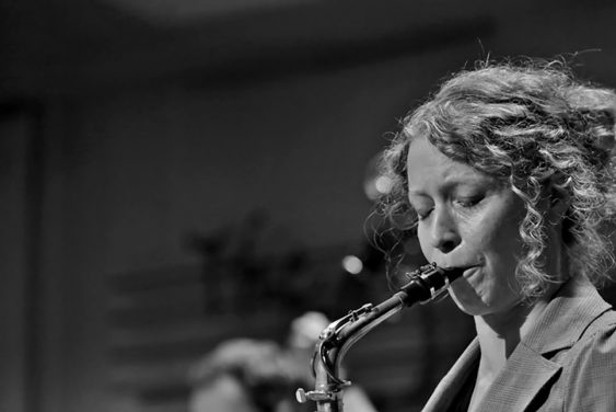 A black and white photo of Kasey Knudsen playing the saxophone.
