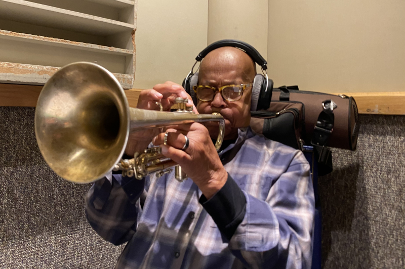 A photo of Eddie Henderson playing the trumpet with headphones on at Wide Hive Studios.