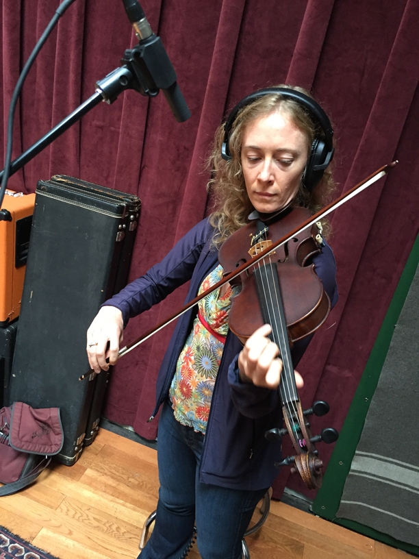 A photo of Laurel Thomsen with her violin, at the Wide Hive Studio.