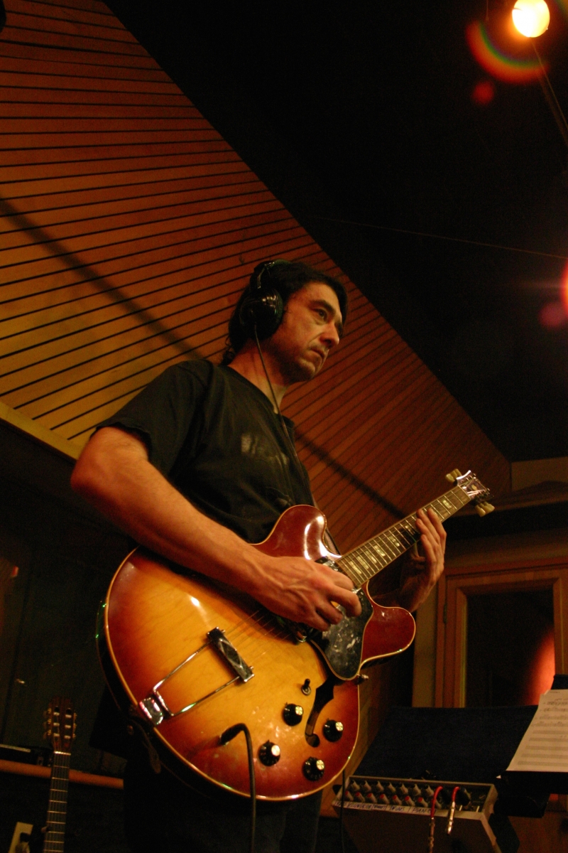 A photo of Mike Ramos playing guitar in the Wide Hive Studios.