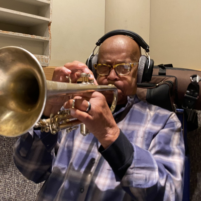 A photo of Eddie Henderson playing the trumpet with headphones on at Wide Hive Studios. A photo of Eddie Henderson playing the trumpet with headphones on at Wide Hive Studios.