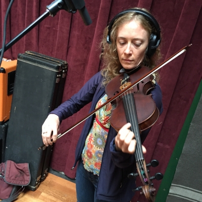 A photo of Laurel Thomsen with her violin, at the Wide Hive Studio.